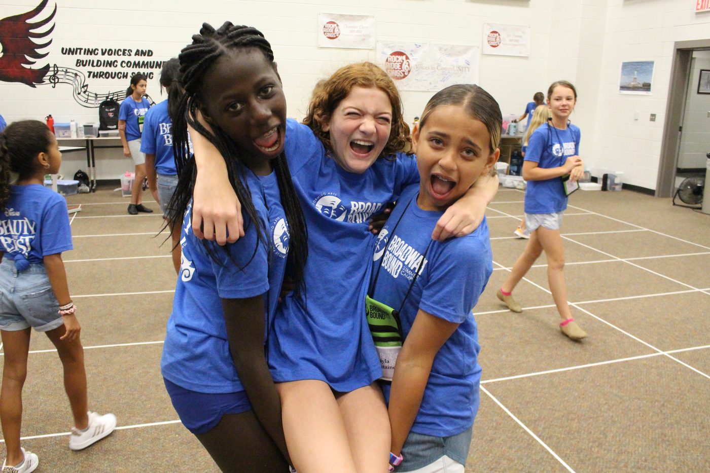 Three campers in blue camp shirts laughing together