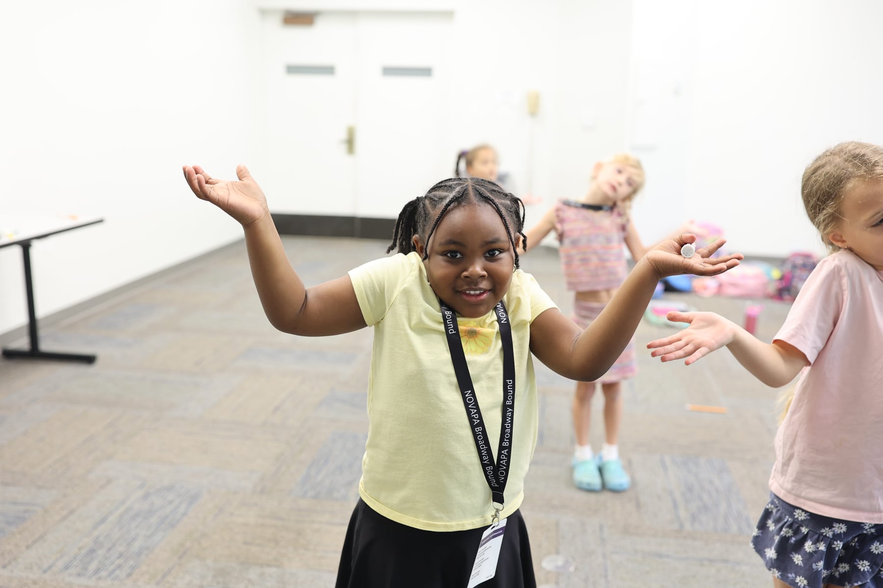 Young performers in a NOVAPA theatre class for ages 5 to 8, arms raised in an open presentational pose