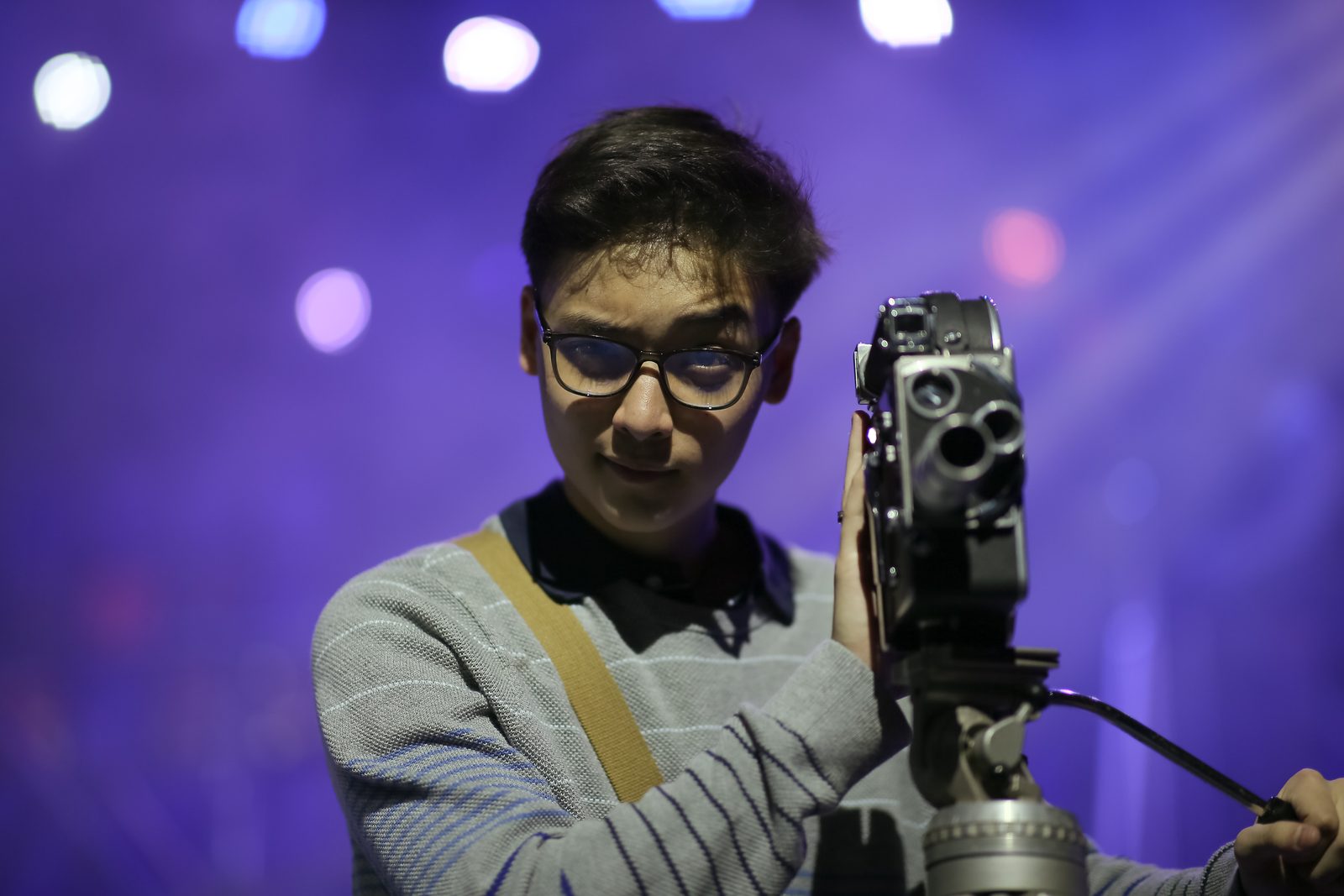 A teen working behind a camera under stage lights